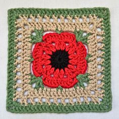 a crocheted square with a red flower on it