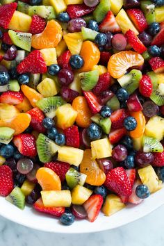 a white bowl filled with fruit salad on top of a marble counter