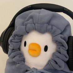 a stuffed penguin wearing headphones and a blue blanket