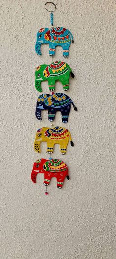 five colorful wooden elephants hanging on the wall in a row, each painted with different colors