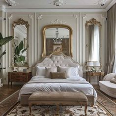 an elegant bedroom with white walls and gold trimmings, large mirror above the bed