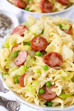 two bowls filled with pasta, peas and sausage on top of a white table cloth