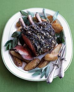 a white plate topped with steak, potatoes and green leafy garnishments