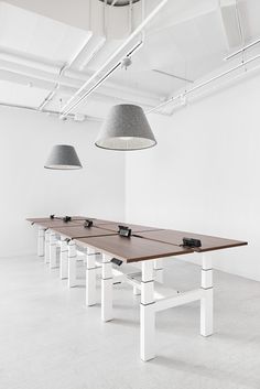 a long table with two lamps hanging from it's sides in an empty room