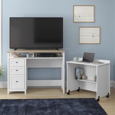 a flat screen tv sitting on top of a white desk next to a blue wall