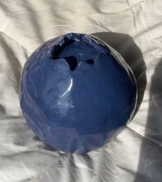 a blue vase sitting on top of a white sheet