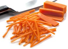 chopped carrots on a cutting board next to a knife