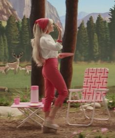 a woman standing next to a pink lawn chair in front of a forest with deer