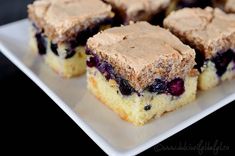 several pieces of blueberry coffee cake are on a white plate with black tablecloth