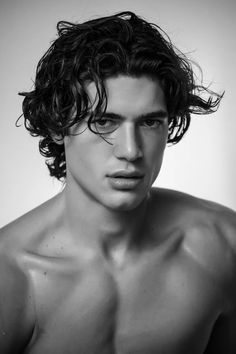 black and white photograph of a shirtless man with curly hair looking at the camera