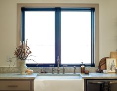 a kitchen sink sitting under a window next to a dishwasher and counter top