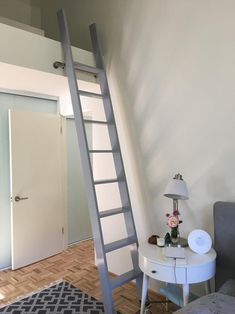 a ladder leaning up against the wall in a bedroom next to a table with a lamp on it