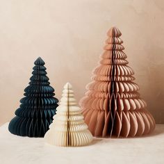 three origami christmas trees in various colors and sizes on a white countertop