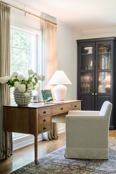 a living room filled with furniture and a book shelf next to a window covered in curtains