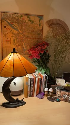 a lamp sitting on top of a desk next to a book case and vase with flowers