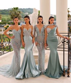 three beautiful women standing next to each other in front of a fountain wearing evening gowns