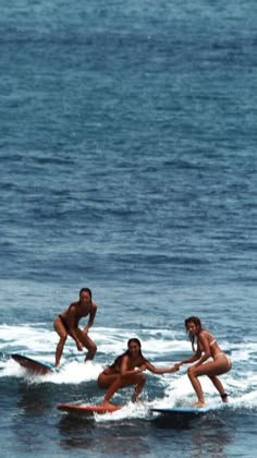 three women on surfboards riding waves in the ocean