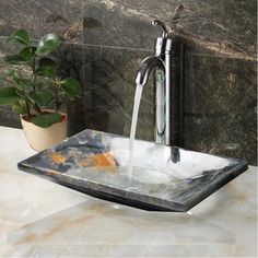 a bathroom sink that has a faucet running from it's side and a potted plant next to it