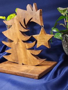 a wooden christmas tree on a stand next to a potted plant