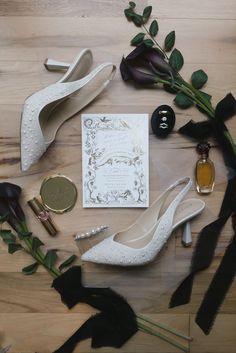 wedding items laid out on top of a wooden table next to flowers and perfume bottles