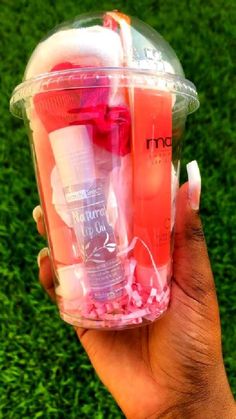 a person holding up a plastic container filled with different types of beauty products on top of green grass