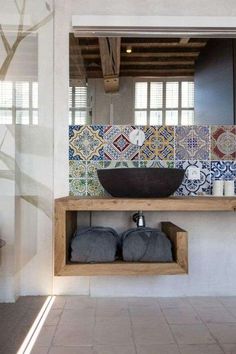 a bathroom with blue and white tiles on the wall, sink and mirror in it