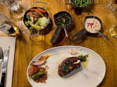 a wooden table topped with white plates filled with food and utensils on top of it