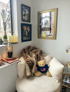 a teddy bear sitting on top of a white chair next to a stuffed animal in front of a window