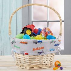 a basket filled with lots of toys on top of a wooden table next to a window