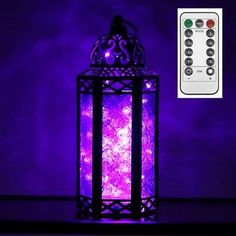 a purple lit lantern sitting on top of a table next to a remote control controller