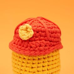 a crocheted yellow and red hat with a white flower