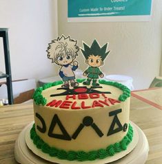 a birthday cake with two cartoon characters on top and green frosting, sitting on a table