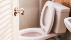 an open door leading to a bathroom with a white toilet and sink in the background