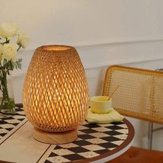 a table topped with a vase filled with white flowers next to a candle on top of a checkered table cloth