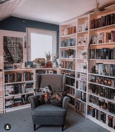 a living room filled with lots of book shelves and a chair in front of a window