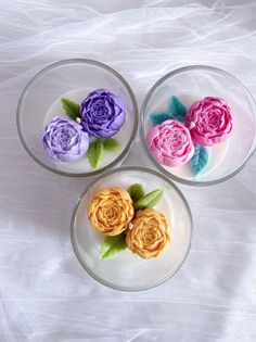 three glass bowls filled with flowers on top of a table