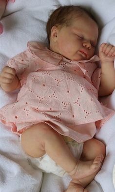 a baby doll that is laying down on a blanket