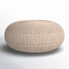 a large round woven ottoman sitting on top of a white floor