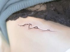 a woman's stomach with a small wave tattoo on her side ribcage