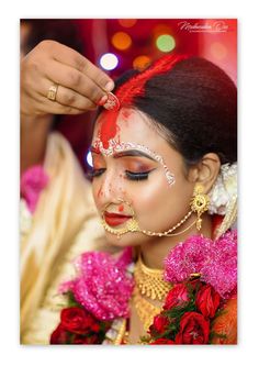 a bride getting her make up done with red and pink flowers in the foreground