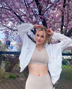 a woman posing in front of a tree with pink flowers