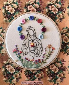 a cross stitched picture of a woman holding a flower in her hands and surrounded by flowers