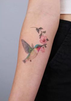 a small hummingbird with pink flowers on its arm