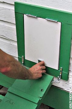 a man is painting the side of a house with green paint and white paneling