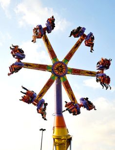 an amusement park ride with people riding on it's sides and in the air