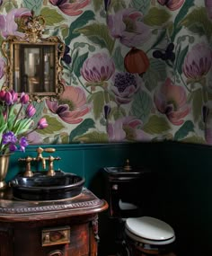 a bathroom with floral wallpaper and an old fashioned sink in front of a mirror