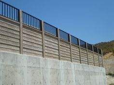 a skateboarder doing a trick on the side of a concrete wall with metal railings