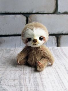 a small stuffed slotty sitting on top of a white table next to a brick wall