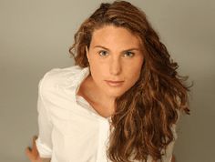 a woman with long hair is posing for the camera, wearing a white shirt and jeans