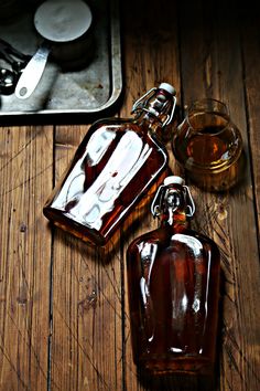 an empty glass bottle sitting on top of a wooden table next to a metal tray